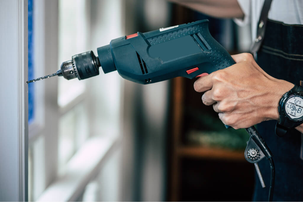 carpenter holds the drill-and-drills the windows